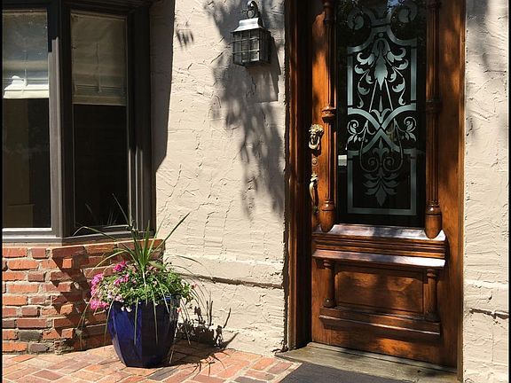 Mahogany entry door with wrought iron coach light beside the sunny five- window bay.