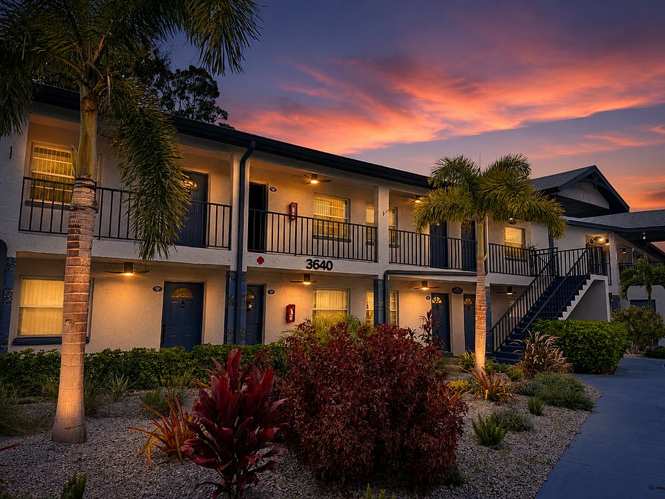 Charming apartment building exterior at sunset, featuring lush landscaping and inviting warm lighting.