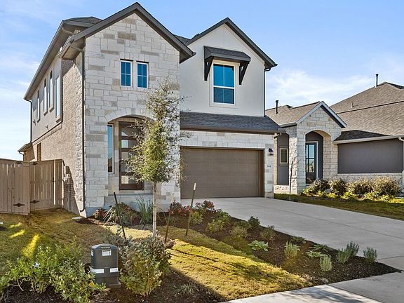 A two-story residential house with a stone exterior, a garage, and a well-landscaped front yard with