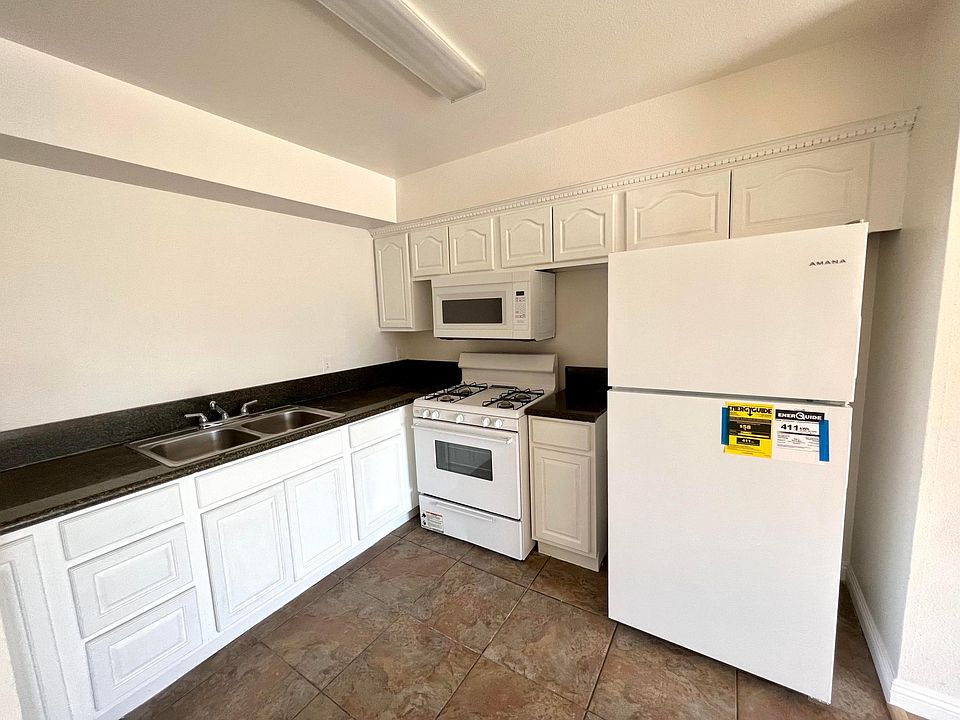 Kitchen with white cabinets, granite countertop, and newly installed microwave & refrigerator!