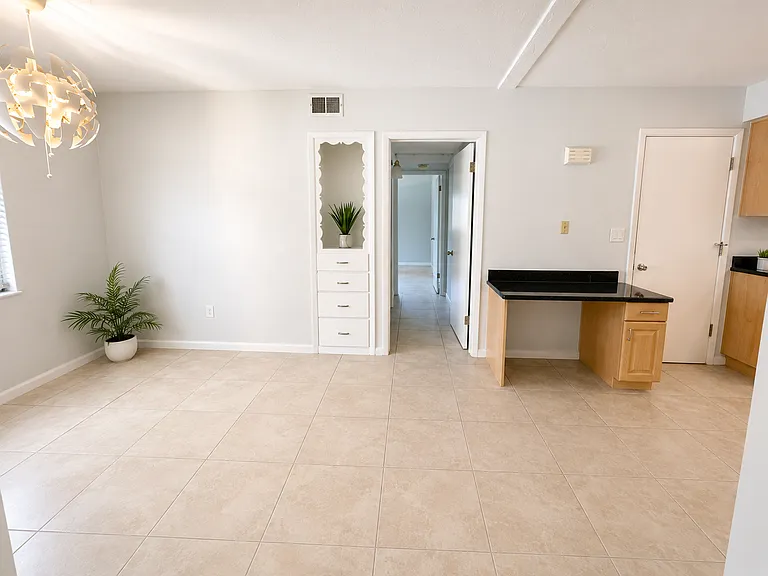 Kitchen Dining Area, facing hallway to third bedroom and bathroom. Kitchen has a build-in desk. Garage door on the right.