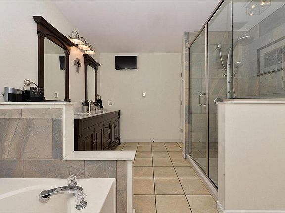 Remodeled master bath offers comfort-height double vanity, tile flooring and surround, and an expanded luxury shower.