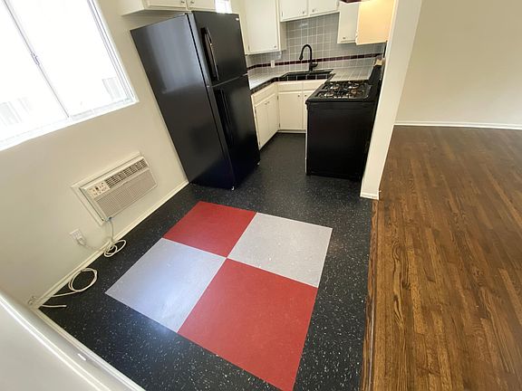Dining nook, tiled kitchen countertops with black faucet, sink, stove, and refrigerator.