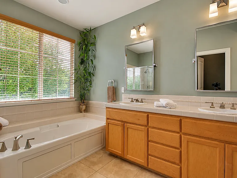 Primary bathroom with dual vanities, soaking tub, and separate shower.
