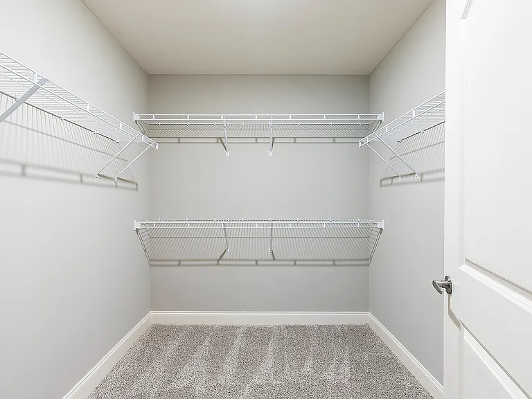 Spacious walk-in closet with sleek wire shelves, perfect for organized storage in a modern apartment.