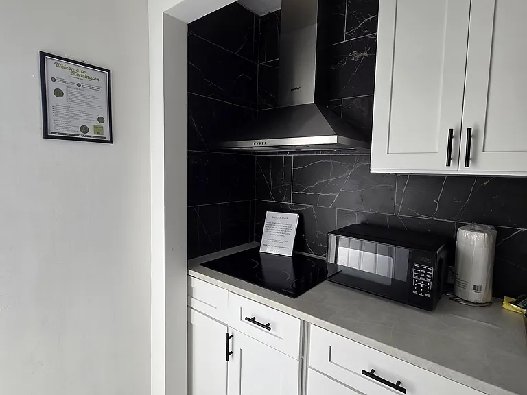 Fully equipped kitchen with stove, cabinets, range hood, microwave, and essentials.