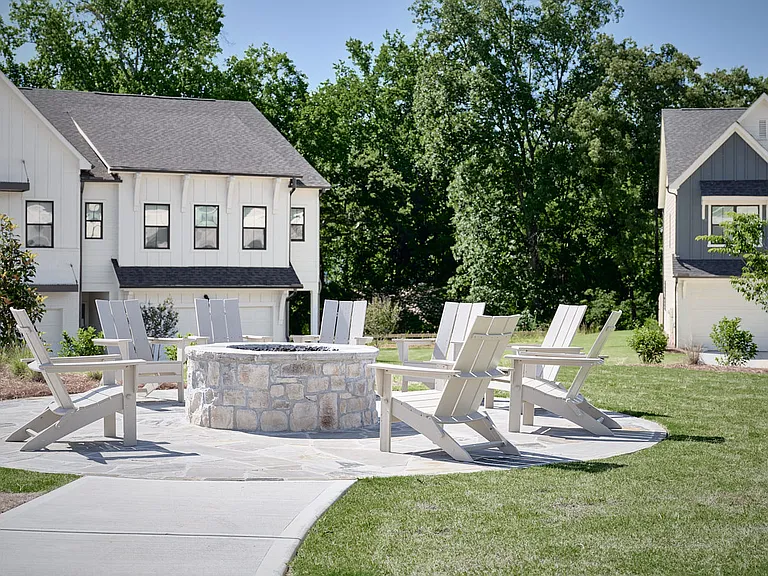 Outdoor gathering space with comfortable chairs and a warm fire pit centerpiece.