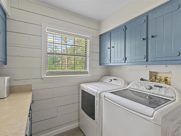 Utility room featuring wood-plank accent wall, built-in cabinetry with blue finish, window with natural light, and countertop space