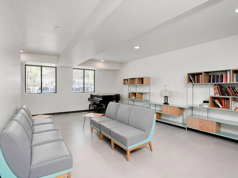 Comfortable community lounge with modern seating, ample natural light, and a shared library.