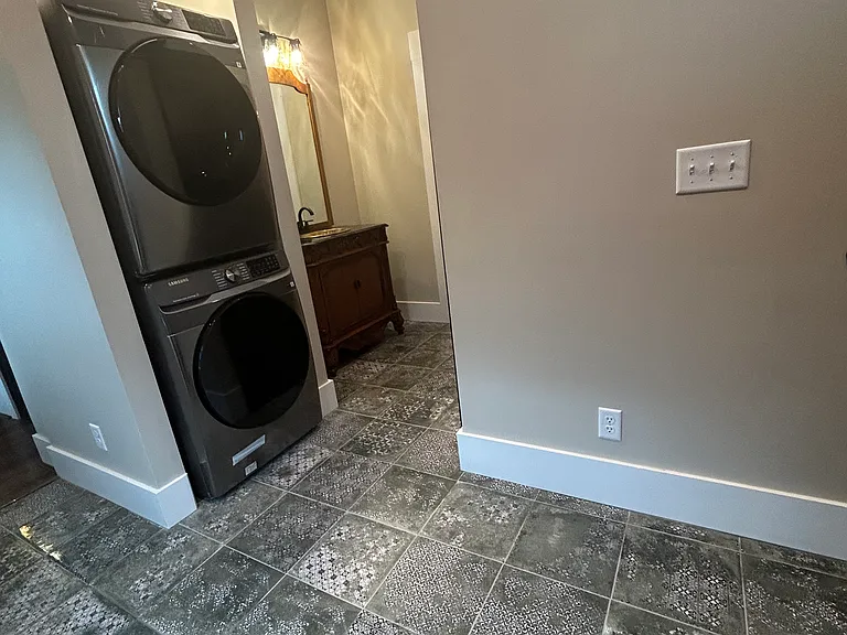 Laundry room with brand new stainless stacked washer and dryer.