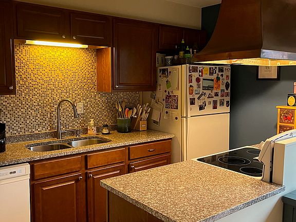 Kitchen with granite countertops, mosaic tile backsplash, dishwasher, oven, fridge, and large sink