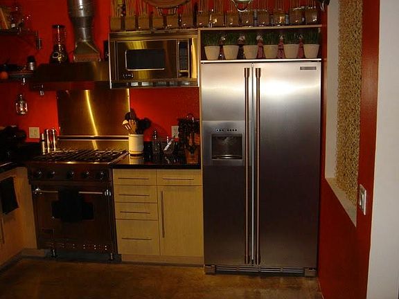 Kitchen has been painted to a neutral silver drop gray. Viking range, microwave, pot rack, granite.