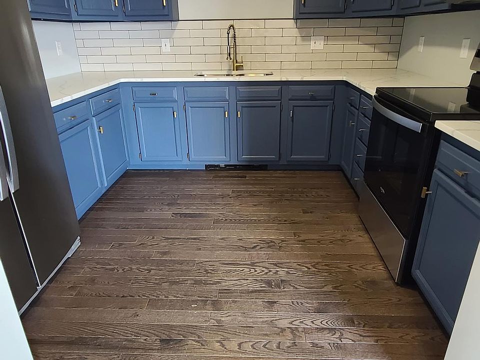 Renovated kitchen with quartz counters, stainless steel appliances, tile backsplash and hardwood floors.