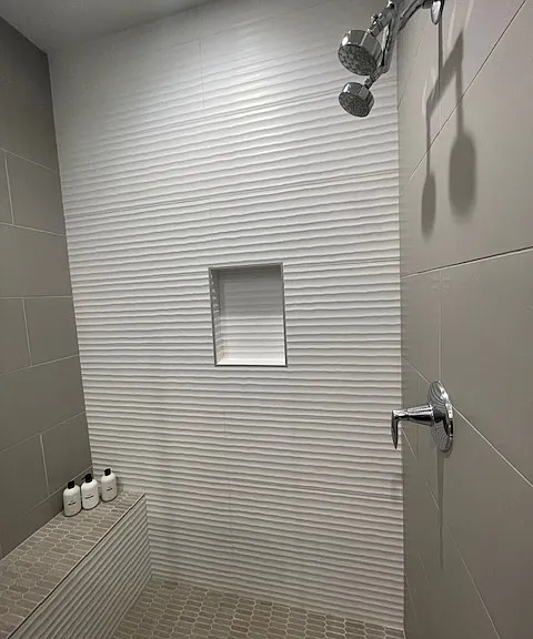 Walk-in shower with bench, glass enclosure.