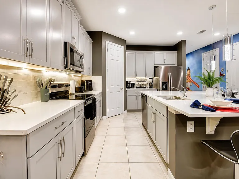 Spacious kitchen with ample shaker cabinetry, quartz counters, and a large island with seating plus stainless appliances.