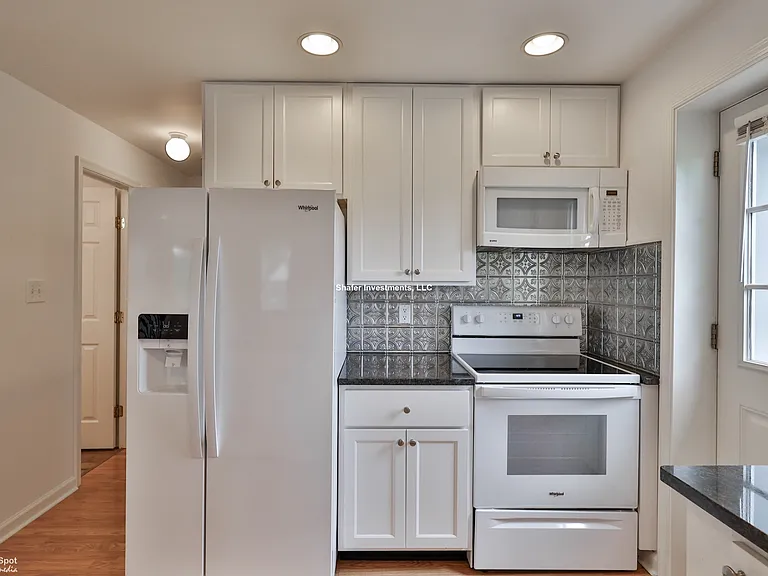 View of the hallway, refrigerator, stove, and microwave