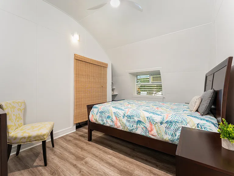 Bedroom 1 featuring vaulted ceilings, luxury vinyl flooring, and tropical-style finishes.