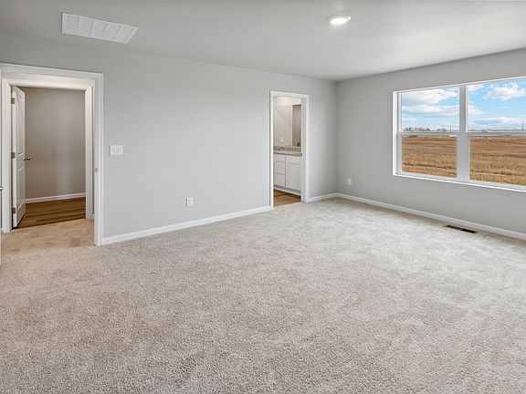 Expansive master bedroom with large windows and attached bathroom.