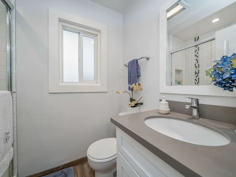 Unit 9 studio with white cabinet, matching mirror & gray quartz countertop.