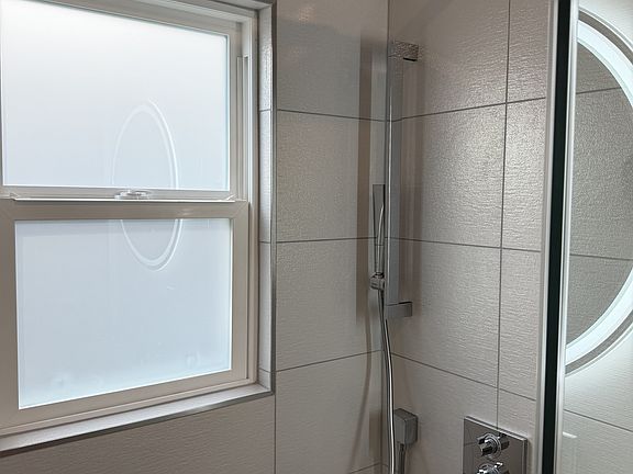 Walk-in rain shower with hand wand.