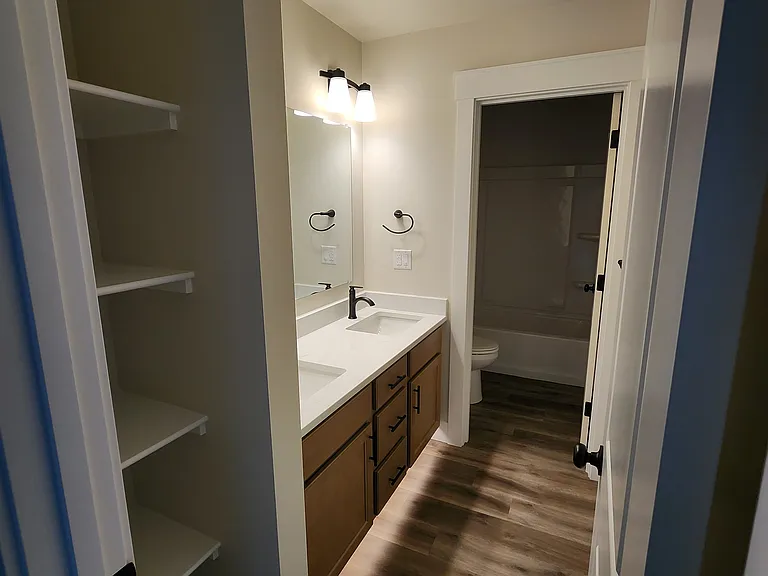 Upstairs double sink, split bathroom with toe-kick lights and linen shelves.