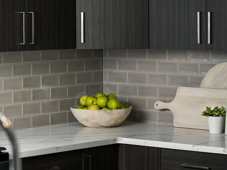 Elegant kitchen corner with soft close dark wood cabinets, modern backsplash, and quartz countertops.