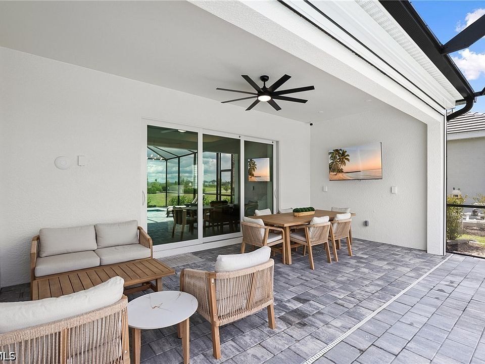 Covered screened lanai with seating group, dining table and ceiling fan overlooking a pool deck, Punta Gorda, Florida