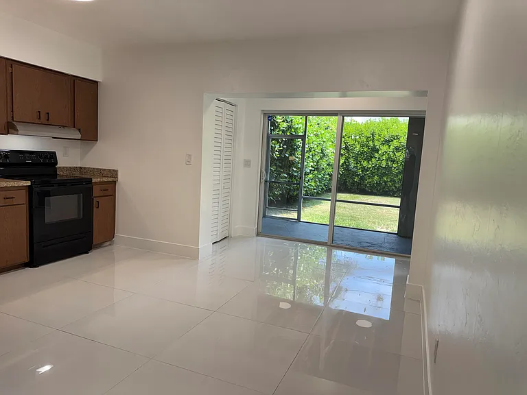 A closer look at the double wide sliding glass doors from the kitchen-dining area out to the screened-in back porch/ patio to the private, landscaped, fenced backyard.