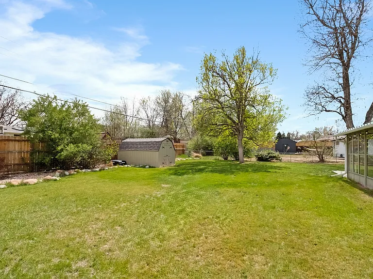 Large backyard full of grass and a bonus shed for storage