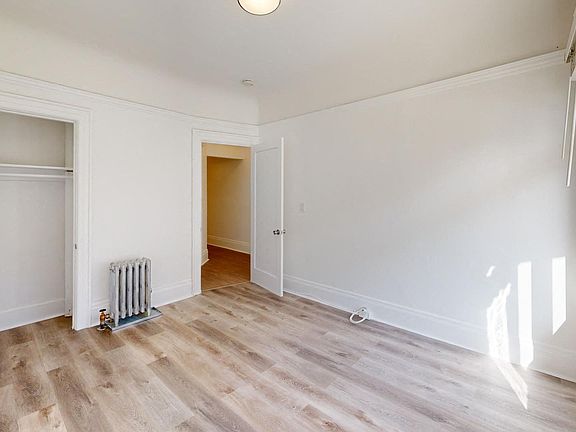 Spacious bedroom with wood-like flooring, closet, and a large window offering natural light