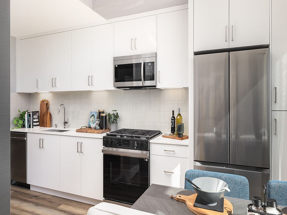 Bright, modern kitchen with sleek stainless steel appliances, abundant white cabinetry, and stylish wood flooring. Perfect for culinary creativity.