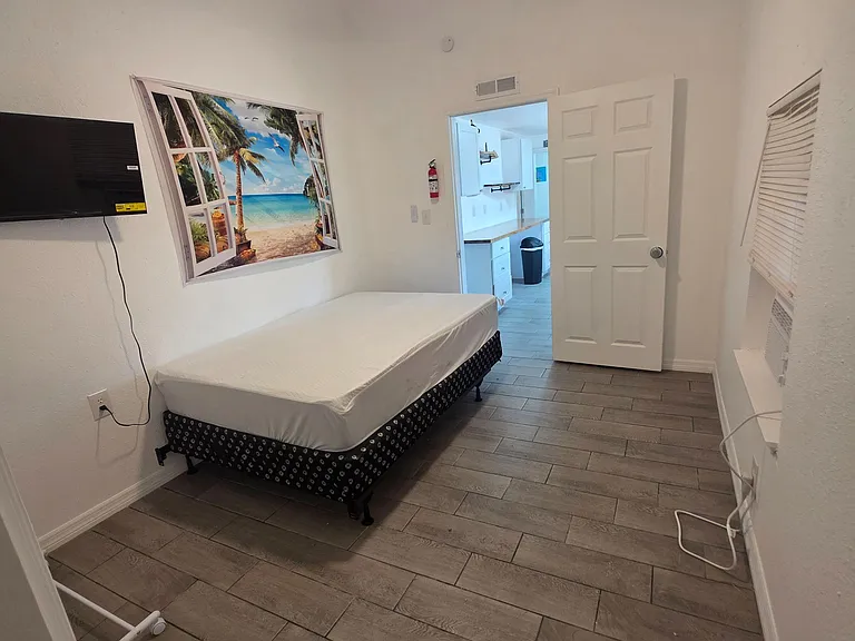 Private bedroom with ceiling fan, tile flooring, and wall-mounted TV, plus convenient access to nearby shared areas.