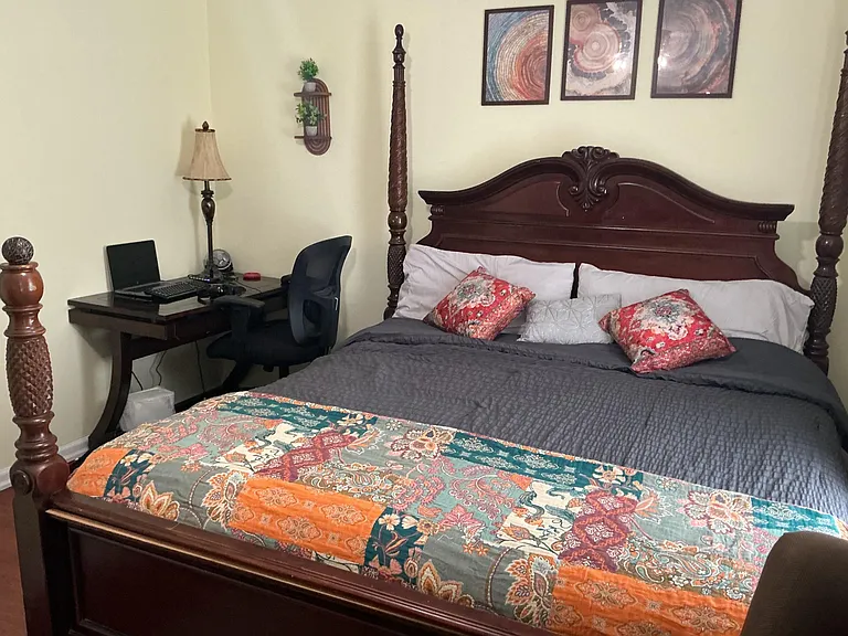 Furnished bedroom with a four-poster bed, coordinated bedding, and a dedicated desk area for work or study.
