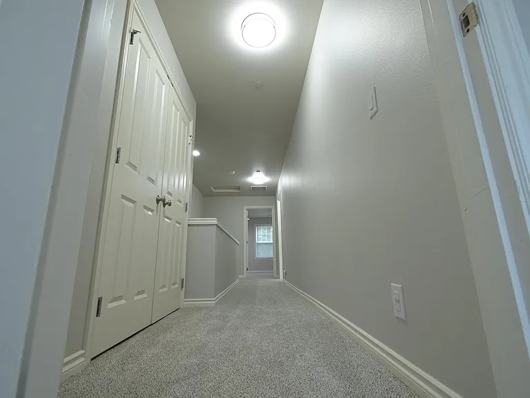 Hallway between bedroom with washer and dryer in doors
