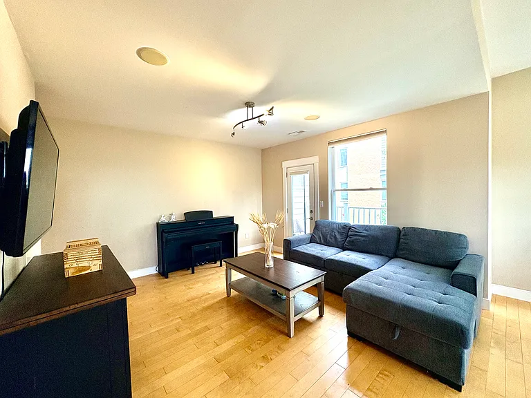 Spacious living room area with Sofa, coffee table and TV. 
Piano in the picture will be removed.