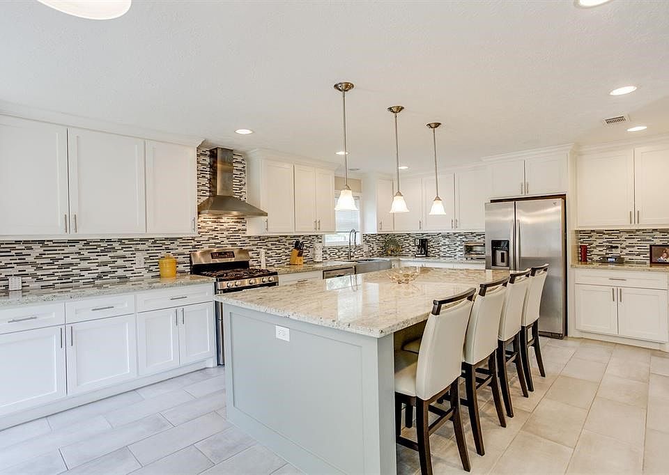 Luxurious kitchen with with huge island, breakfast bar, stainless steel appliances, built in microwave, recess lighting, abundant cabinet space, granite countertops, brush finished tile floors and a beautiful tile backsplash!
