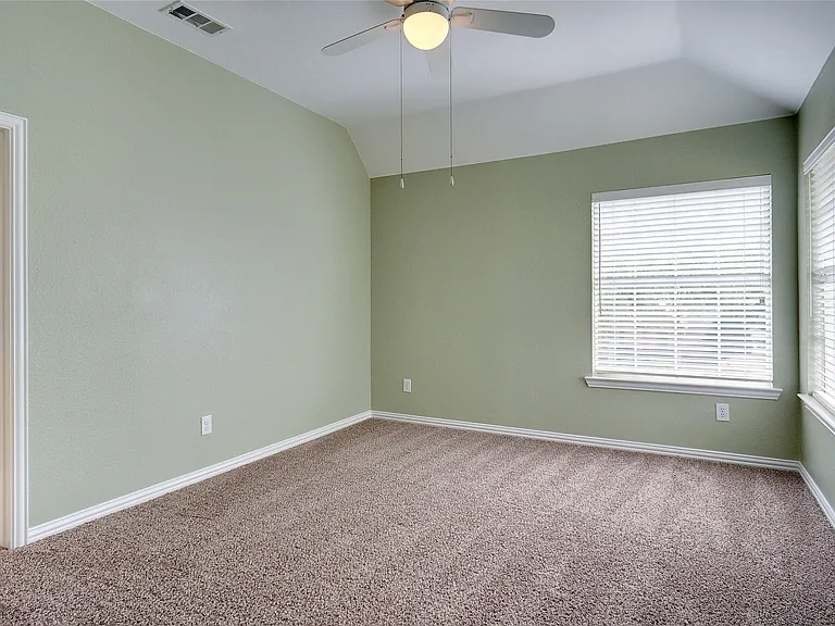 Carpeted room featuring a vaulted ceiling and a ceiling fan with integrated lighting