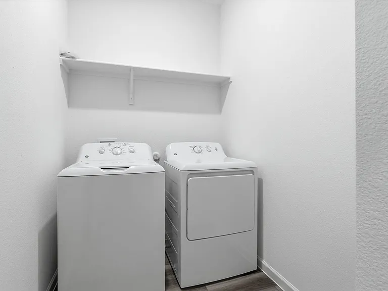 Dedicated laundry area featuring a shelf, wood-finish flooring, white walls, and base molding