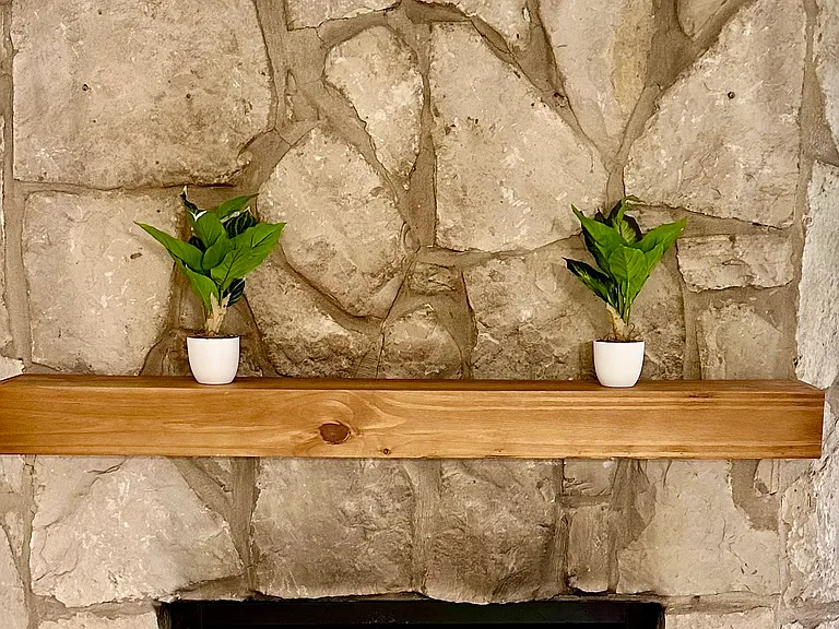 Floor to ceiling stone fireplace with wood mantel adds charm and character.