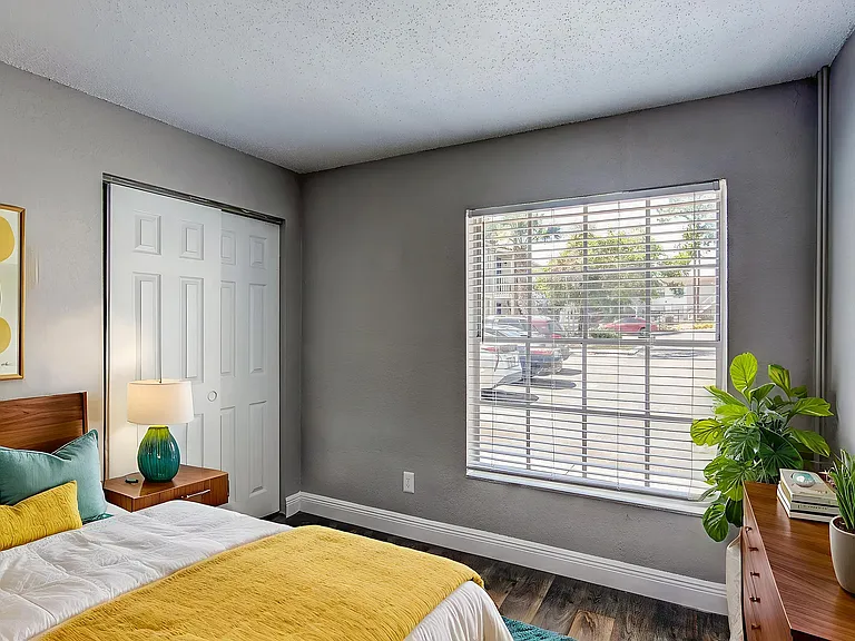 Bright and inviting bedroom with large window, modern decor, and vibrant yellow accents, creating a cozy and stylish atmosphere.