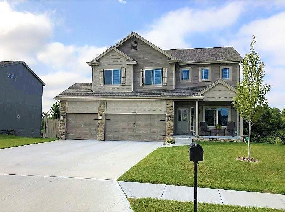 Front view with covered front porch and 3 car wide driveway and garages. Handy fenced trash can area, to keep them out of the garage
