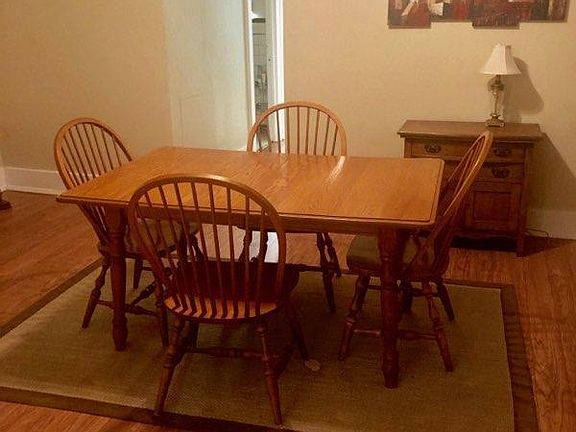 Dining room with included table and chairs, wall hanging and hutch with lamp.