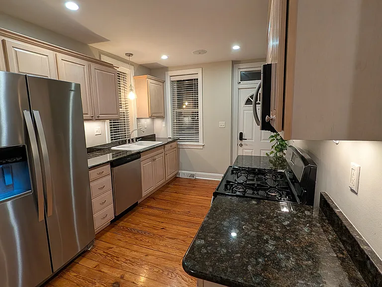 Kitchen with under cabinet lighting, a gas range large side-by side refrigerator with ice maker, dish washer, built-in microwave and a garbage disposal.