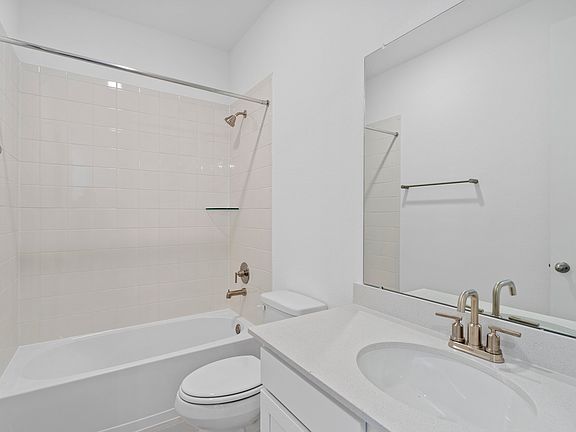 The secondary bath features tile flooring, white cabinetry and light countertops and a shower tub co
