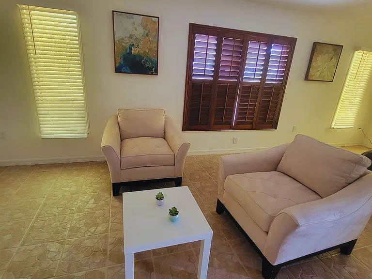 Inviting seating area with comfortable chairs, a coffee table, and sunny windows.