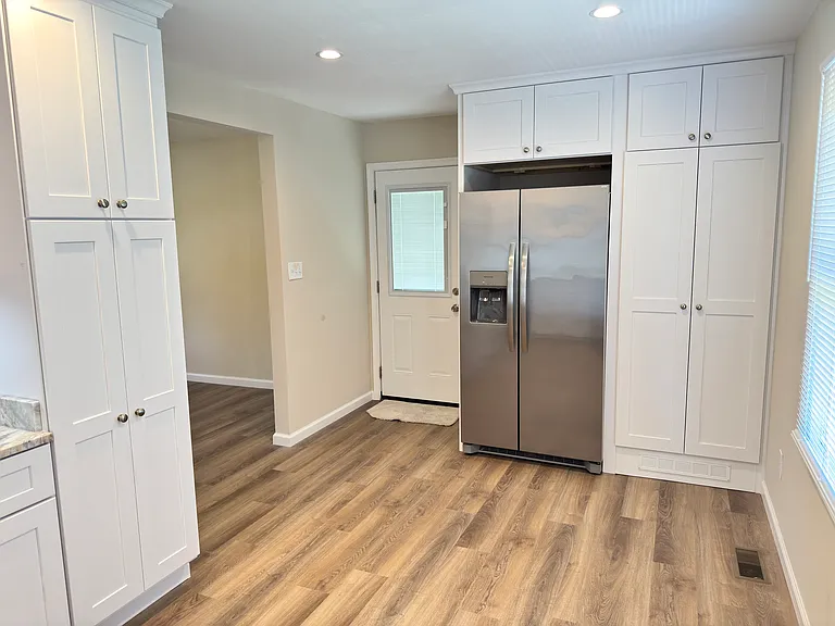 Kitchen looking at side door, fridge, and washer/dryer cabinet.