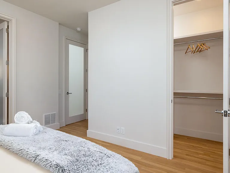 Primary bedroom showcases new artwork, a queen bed, floor-to-ceiling windows for natural light, and an attached bathroom for added convenience.