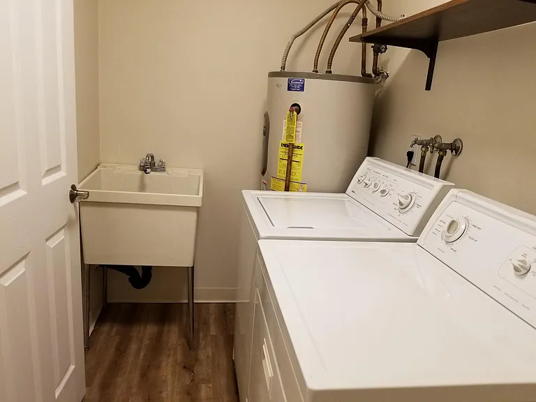 Utility room with sink, washer, and dryer connects the garage with the back of the kitchen.
