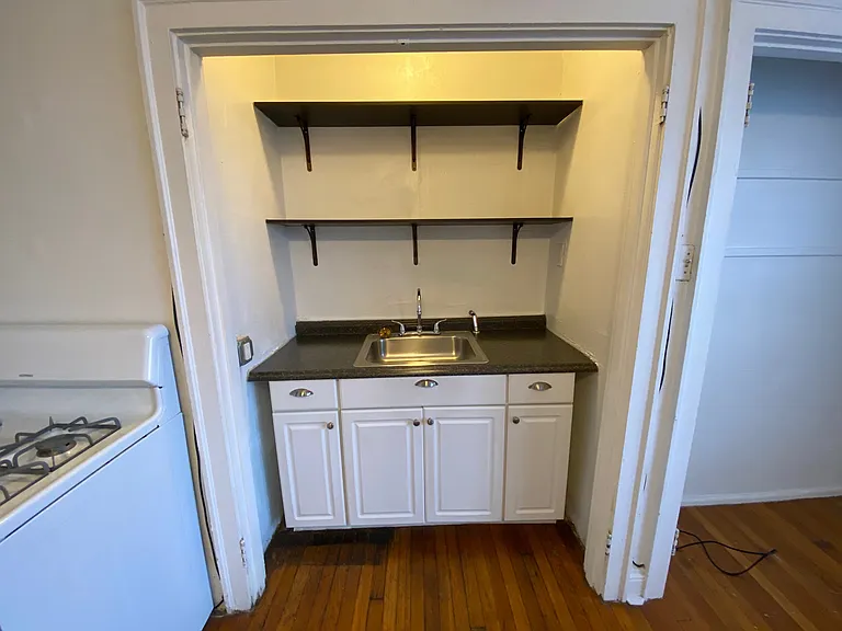 Tucked into a charming alcove, the sink and open shelving create a cozy workspace.