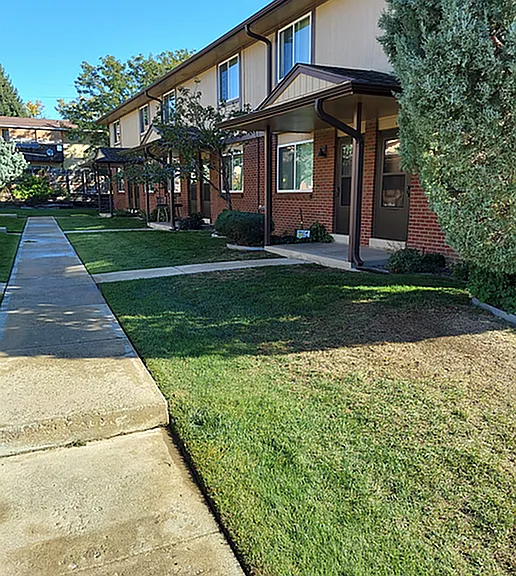 Charming townhouse exterior with a lush green landscape, perfect for serene living.